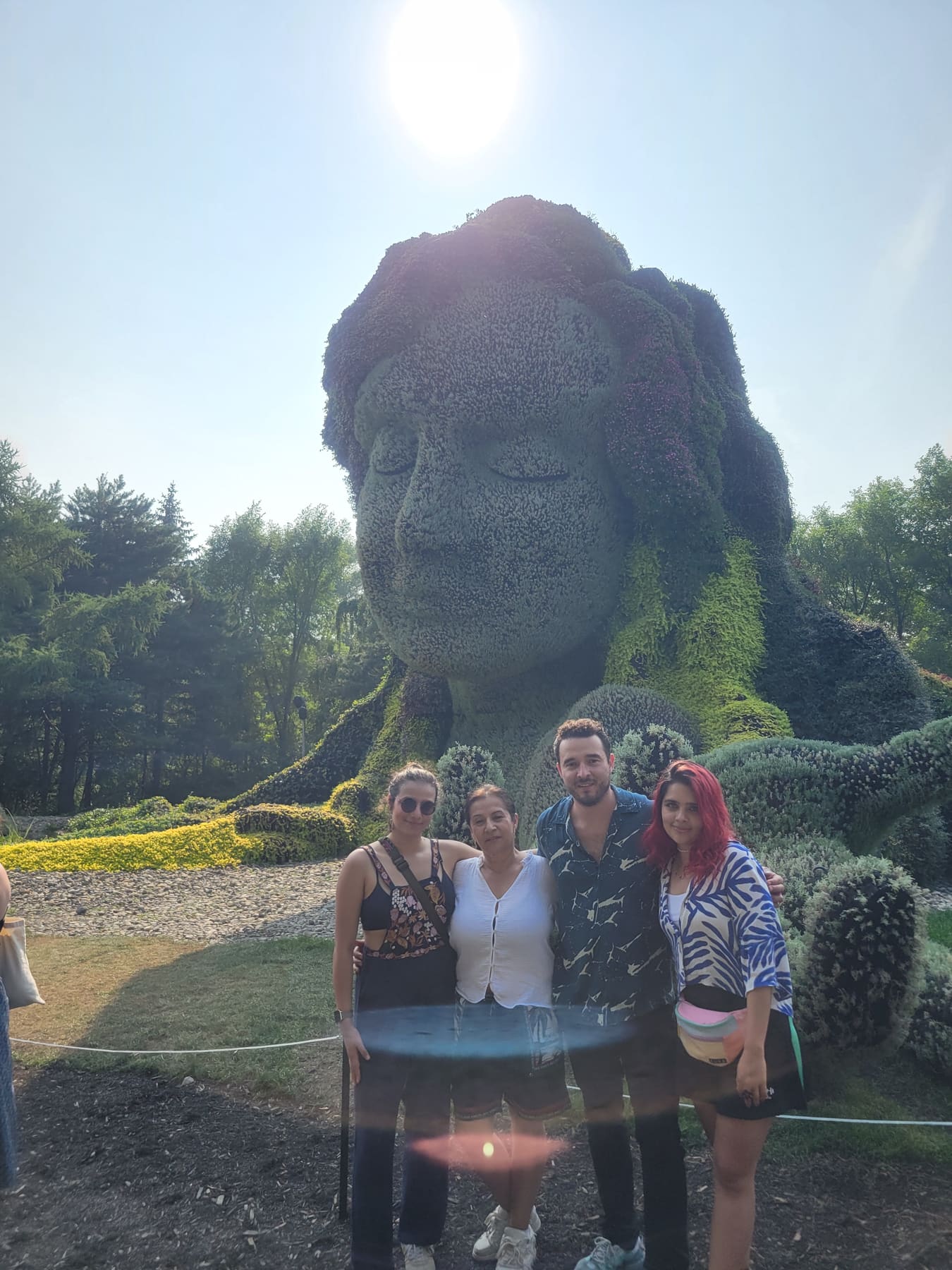 Beatriz con familia frente a una escultura de jardín